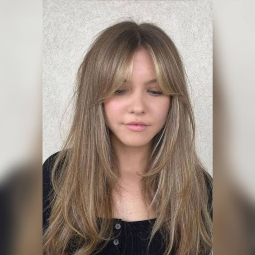 A woman with curly bangs hairstyle softly framing the face.