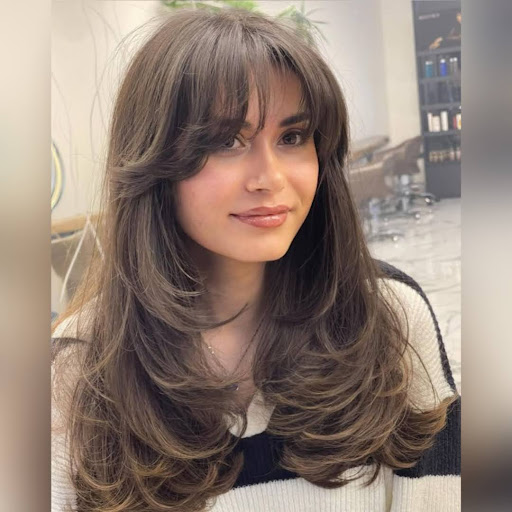 Woman with feathered bangs blended into layered hair.