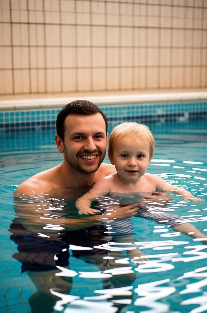 Realistic indoor swimming pool moment between father and son.