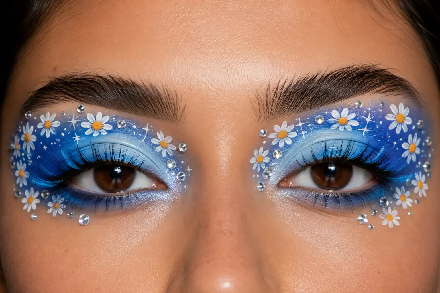Close-up of both eyes with blue eyeshadow, tiny white daisies, crystal rhinestones, and dramatic lashes