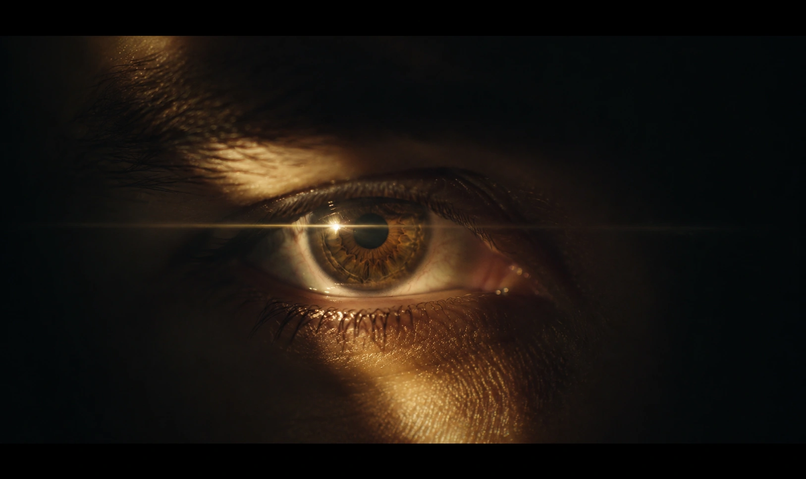 Cinematic close-up of an eye illuminated by a narrow beam of warm light against deep shadows