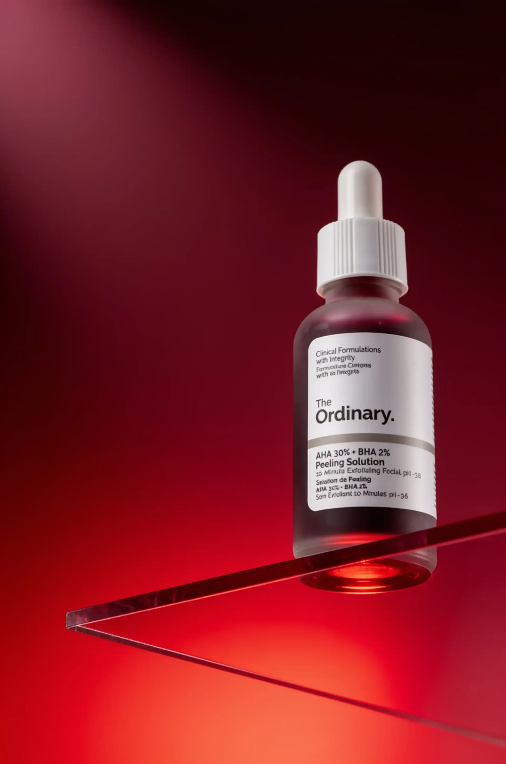 Skincare dropper bottle displayed on a ruby-red acrylic platform.