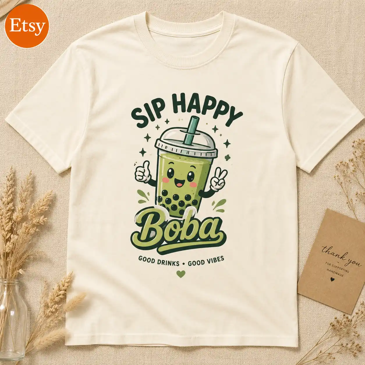 Cream graphic T-shirt styled as a warm handmade Etsy product listing with simple natural props.