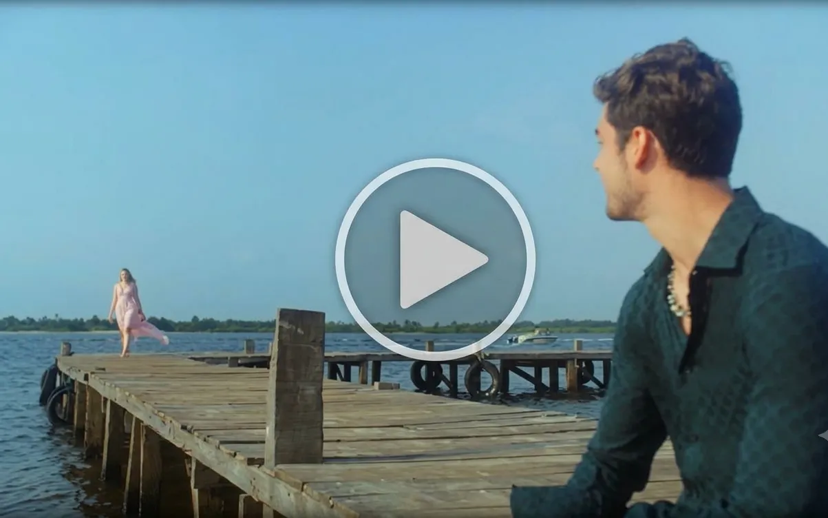 A man sitting on a beach shack waiting for a woman to reach him.Â